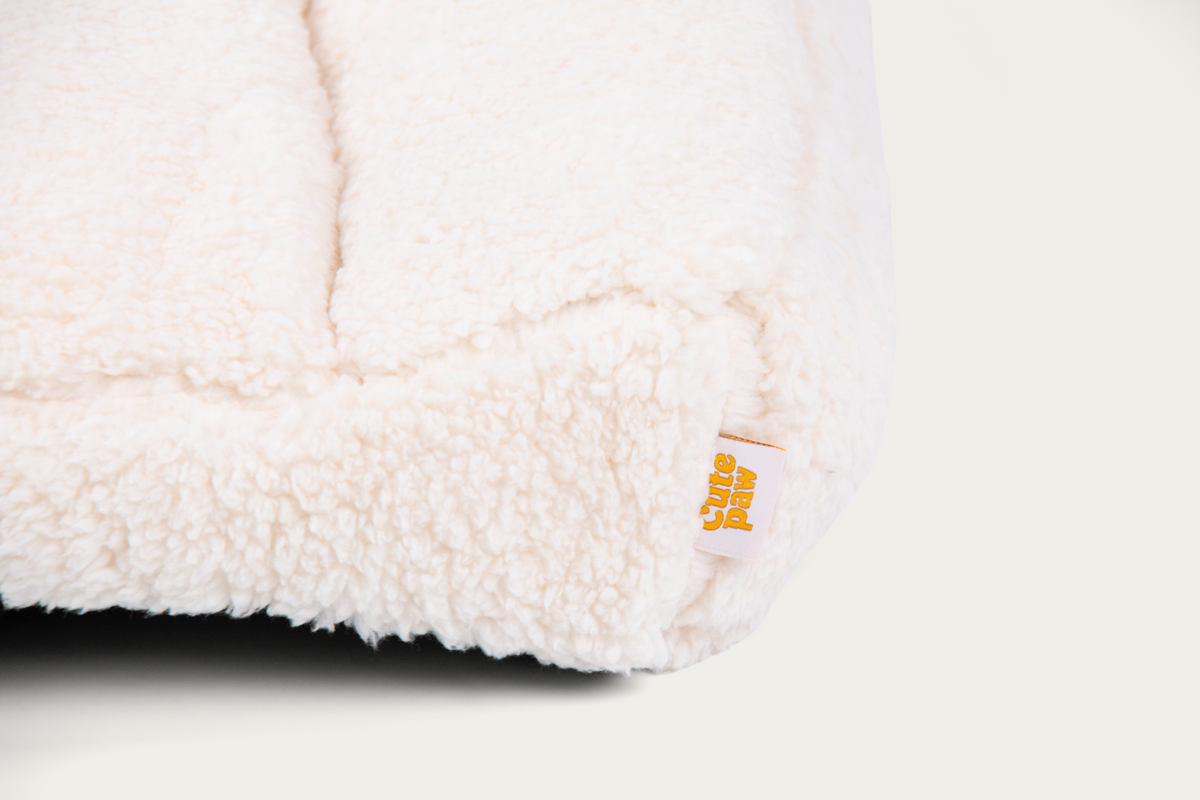 Close-up of the Cloud Open Bolster bed's plush front corner and Cute Paw label